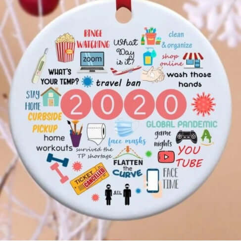 Round ceramic ornament with colorful 2020 pandemic icons and phrases, hanging on a tree.