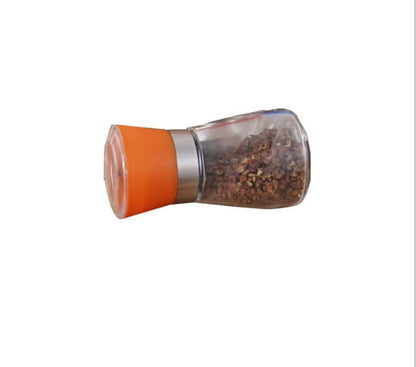Manual spice grinder with orange lid and stainless steel base filled with dried spices