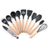 Set of black silicone kitchen utensils with wooden handles, including spatulas, spoons, whisk, and tongs, on white background.