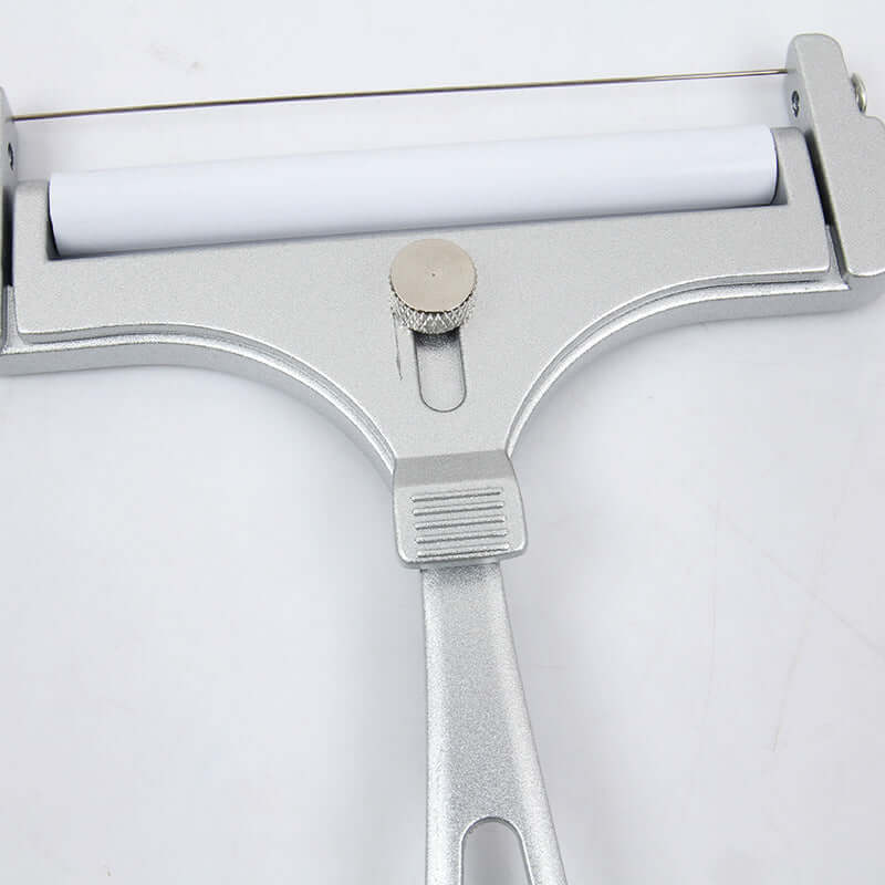 Metal cheese slicer with adjustable wire and white roller on a light surface