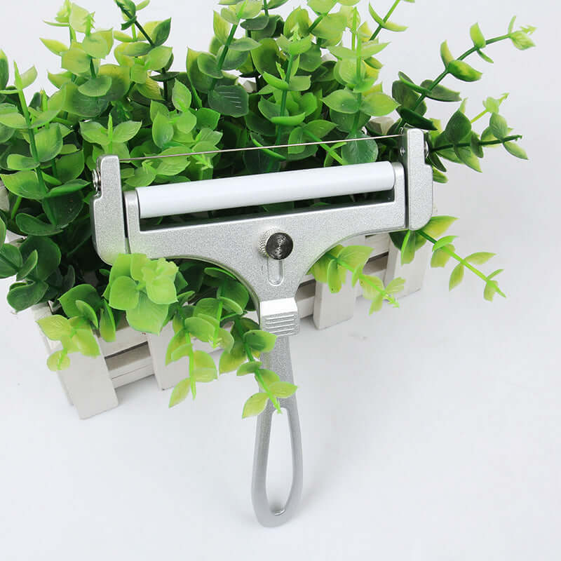 Metal kitchen utensil roller tool on white surface with green plant background