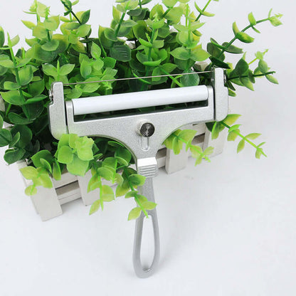 Metal kitchen utensil roller tool on white surface with green plant background