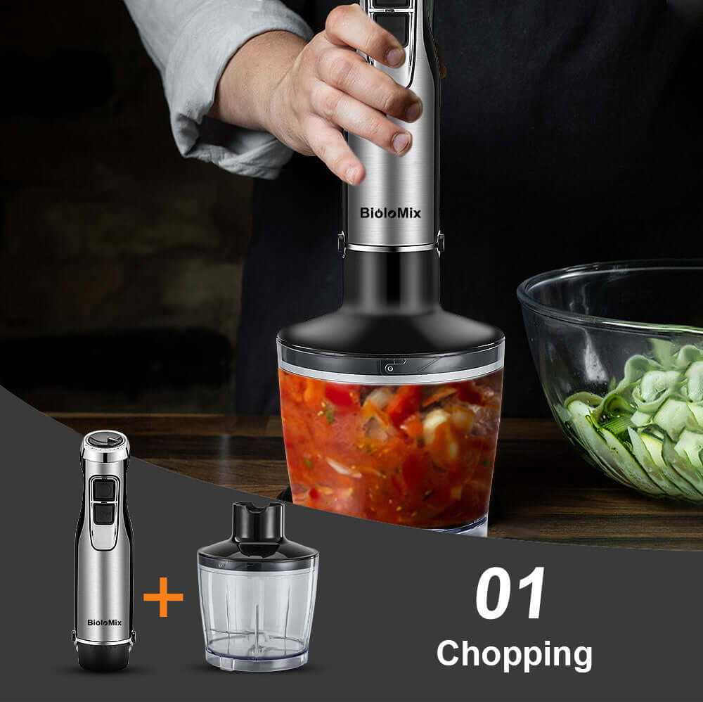 Hand using electric food chopper to chop vegetables in glass bowl on kitchen counter
