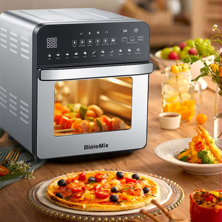 Stainless steel countertop air fryer oven with digital controls, pizza and skewers on table.