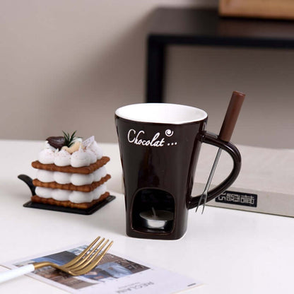 Chocolate fondue mug set with tealight candle, fork, and dessert on modern kitchen table