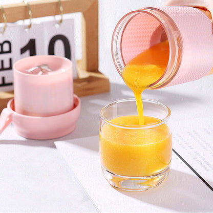 Portable pink blender pouring fresh orange smoothie into a glass on a kitchen table