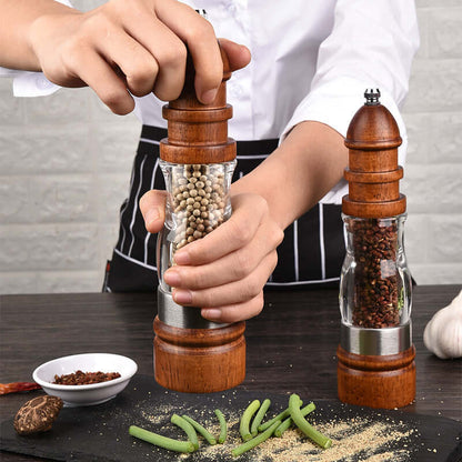 Hand using wooden pepper grinder in kitchen with spices and vegetables on table