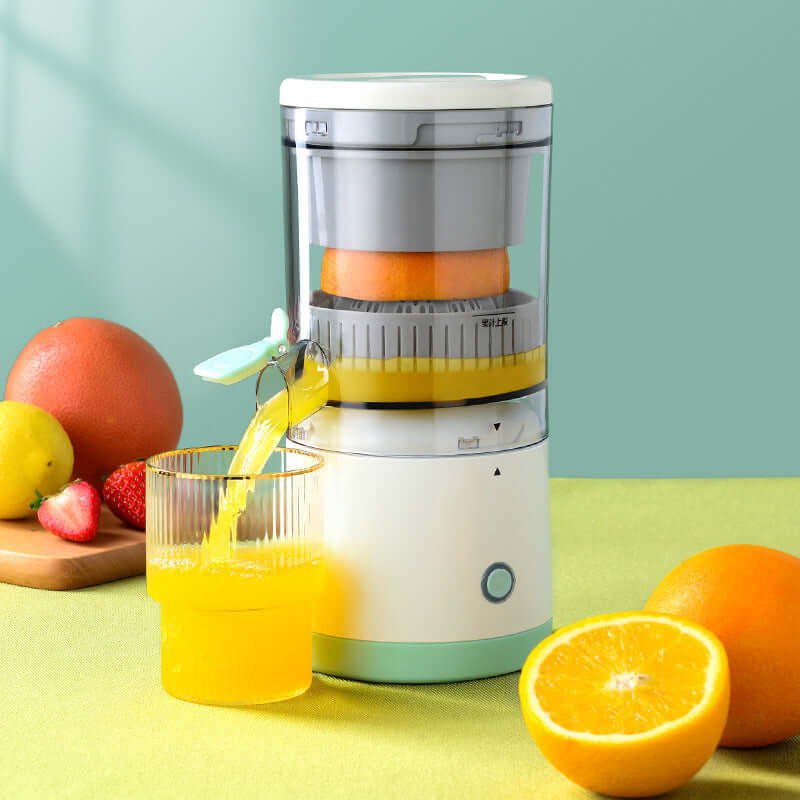 Electric citrus juicer making fresh orange juice with fruit and glass on kitchen counter