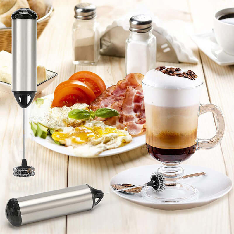 Stainless steel milk frother with cappuccino, breakfast plate, and kitchen accessories.