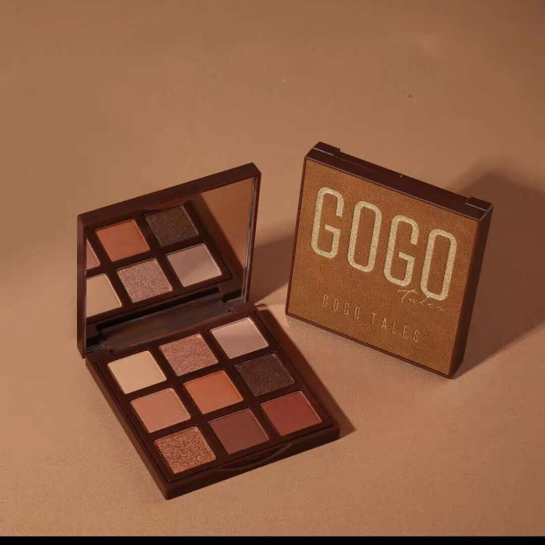 Brown eyeshadow palette with mirror featuring nine neutral and shimmer shades on a tan background.