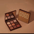 Brown eyeshadow palette with mirror featuring nine neutral and shimmer shades on a tan background.