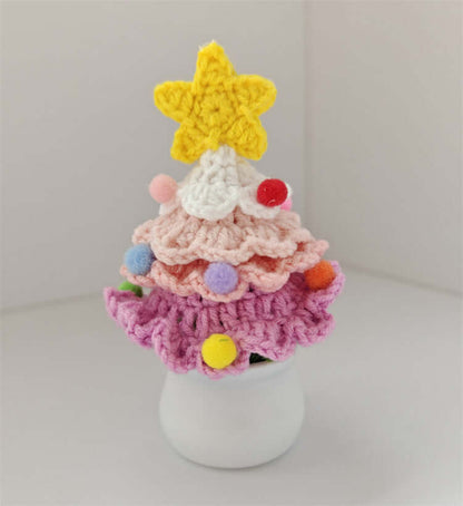 Colorful crochet Christmas tree with a yellow star topper and pom pom ornaments in a white pot