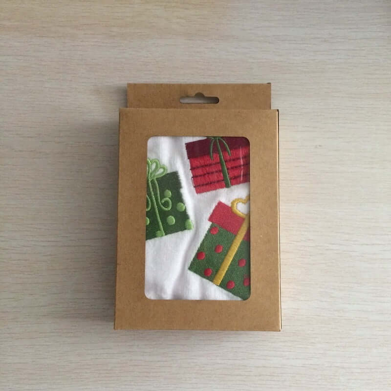 Gift-themed kitchen towel set in brown box with clear window, featuring colorful presents.
