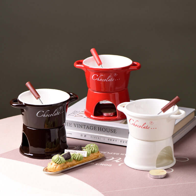 Ceramic chocolate fondue pots in red, black, and white with fondue forks on a table