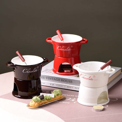 Ceramic chocolate fondue pots in red, black, and white with fondue forks on a table