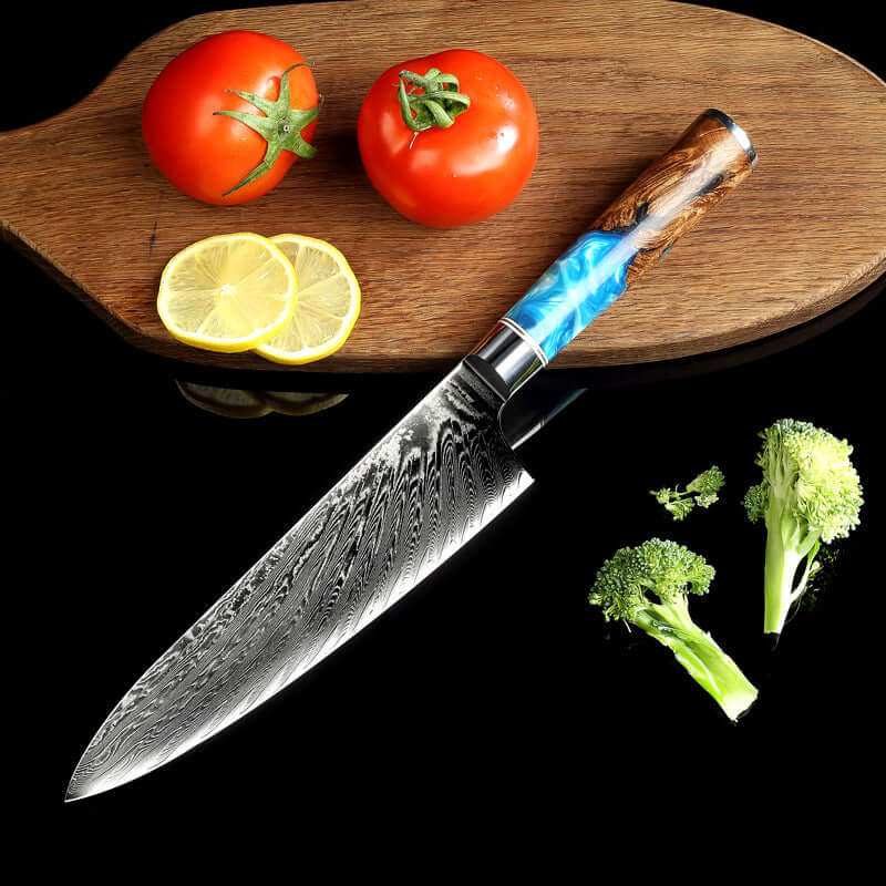 Damascus chef knife with blue resin handle, cutting board, tomatoes, lemons, broccoli