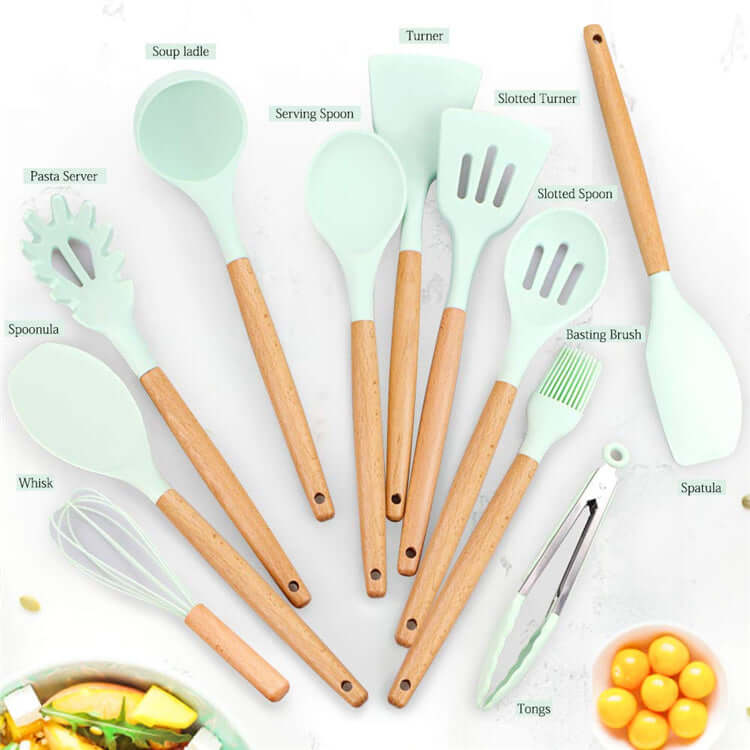 Set of mint green silicone kitchen utensils with wooden handles, including spatula, tongs, whisk, spoons, and pasta server, arranged on a white surface.