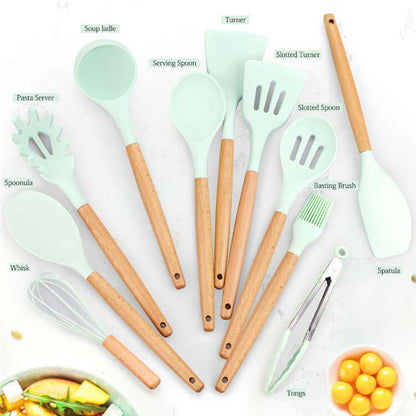 Set of mint green silicone kitchen utensils with wooden handles, including spatula, tongs, whisk, spoons, and pasta server, arranged on a white surface.