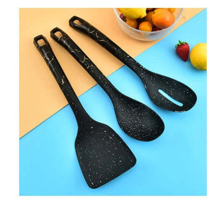 Set of three black speckled kitchen utensils, spatulas and ladle, on a colorful background