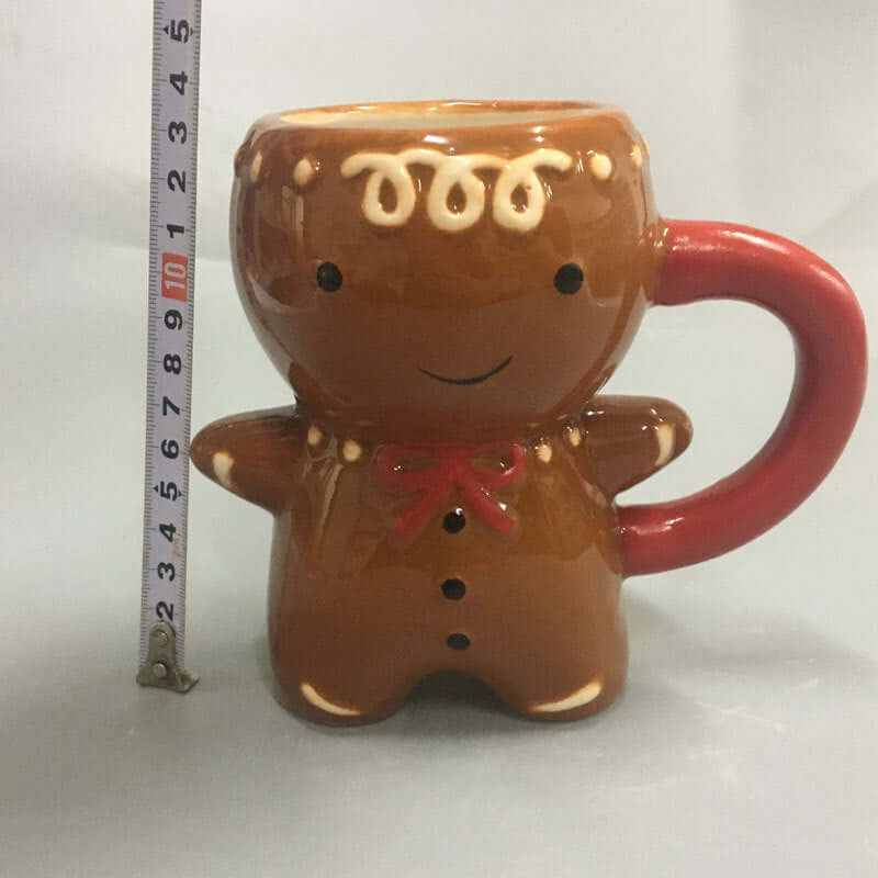 Gingerbread man ceramic mug with red handle and ruler for size reference, kitchen accessory