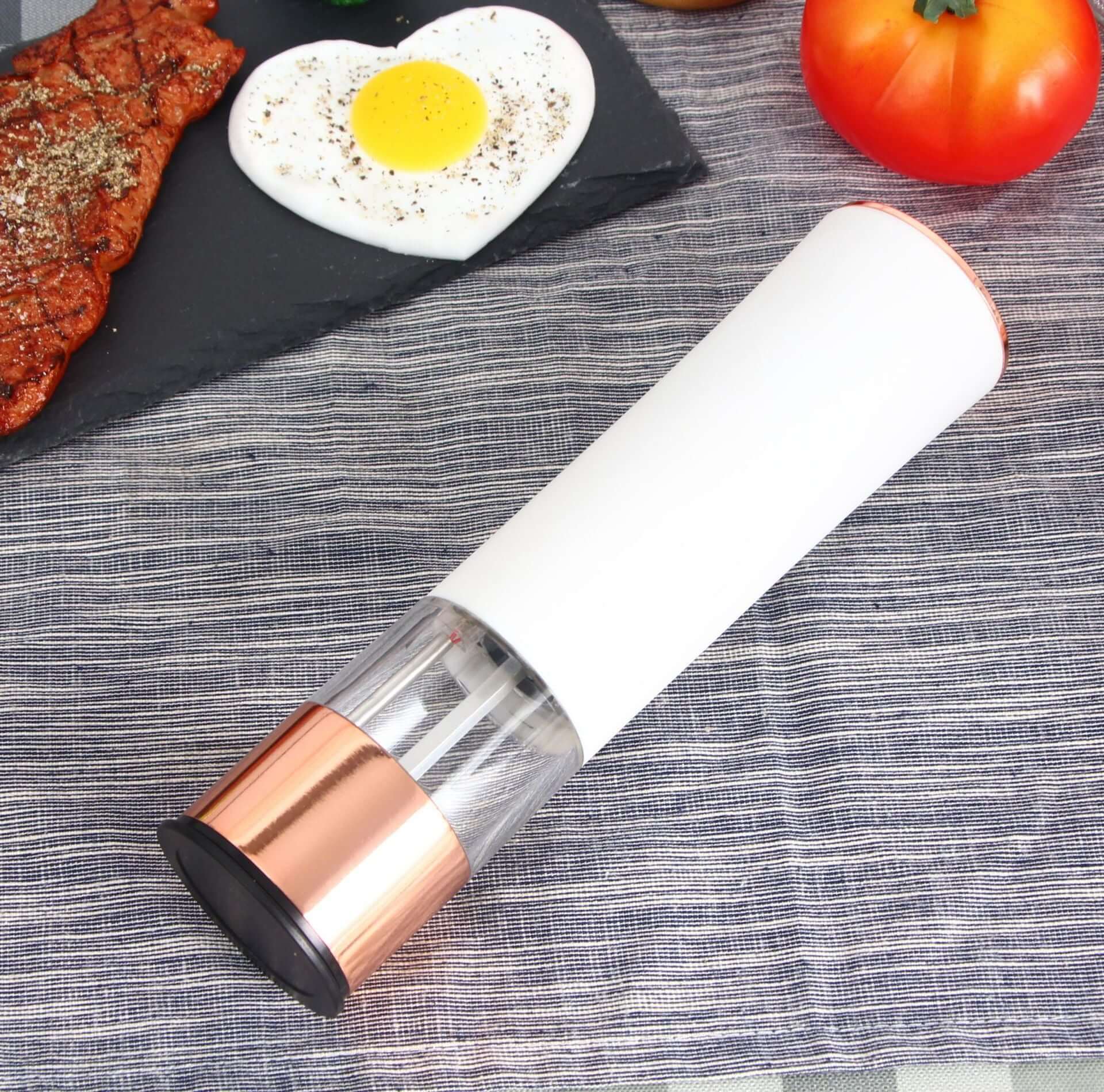 Electric salt and pepper grinder on table with steak, heart-shaped egg, and tomato