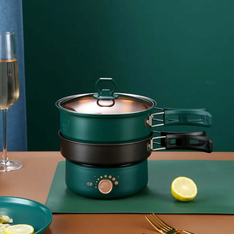 Electric multi-tier steamer pot set with green handles on a kitchen countertop