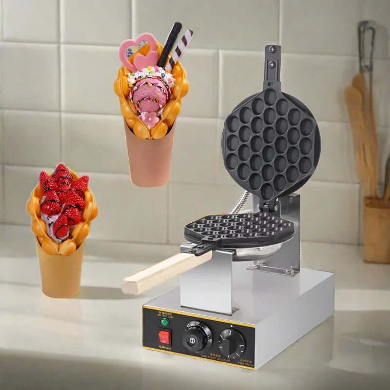 Bubble waffle maker on kitchen counter with two filled bubble waffles, one with strawberries, one with ice cream.
