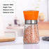Glass spice grinder with orange lid filled with pink Himalayan salt on kitchen counter