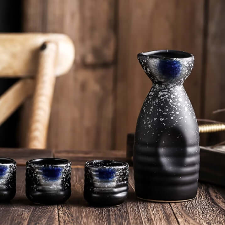 Modern black ceramic sake set with glossy speckled finish on rustic wooden table