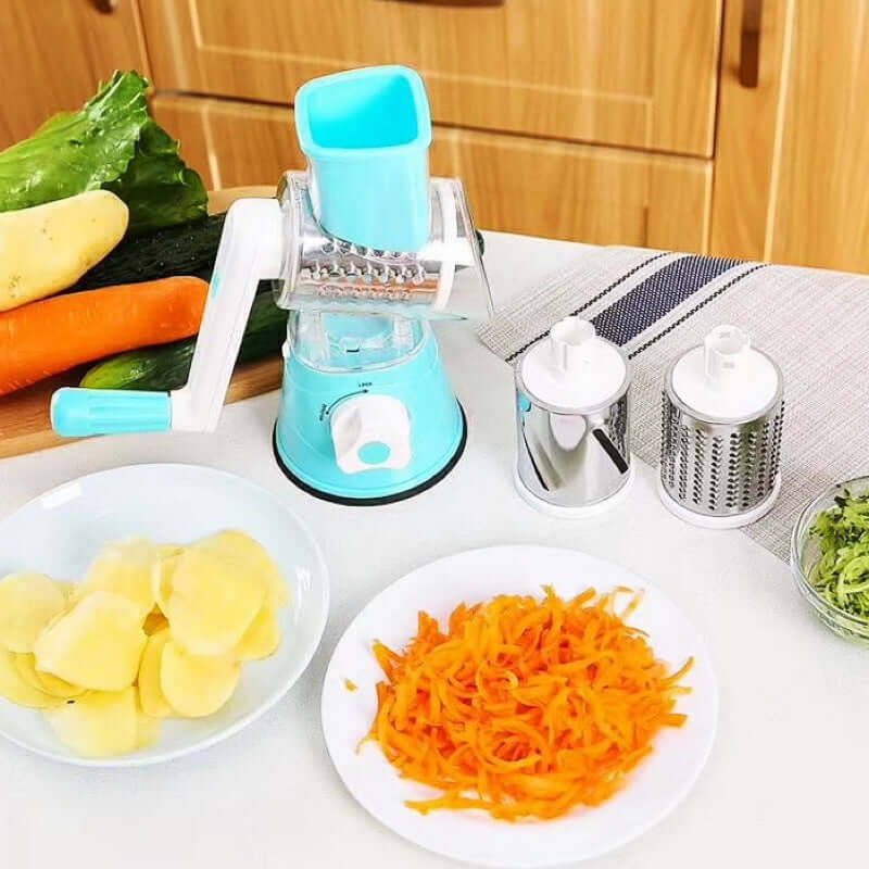 Manual rotary vegetable grater with interchangeable blades and sliced vegetables on kitchen counter