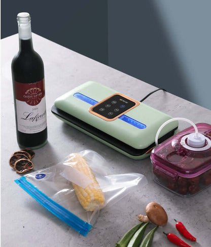 Vacuum sealer machine on kitchen counter with food storage bags, wine bottle and fresh vegetables