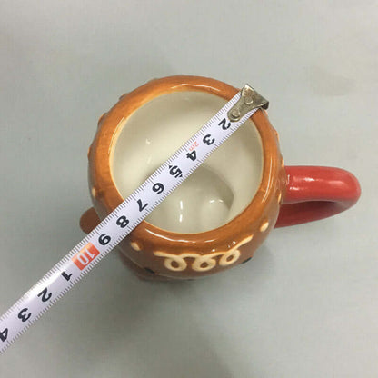 Ceramic mug with orange handle being measured with tape measure on light background