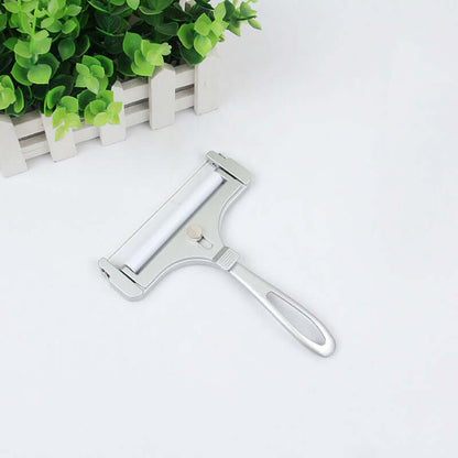 Stainless steel kitchen slicer tool on white background near green plant decor