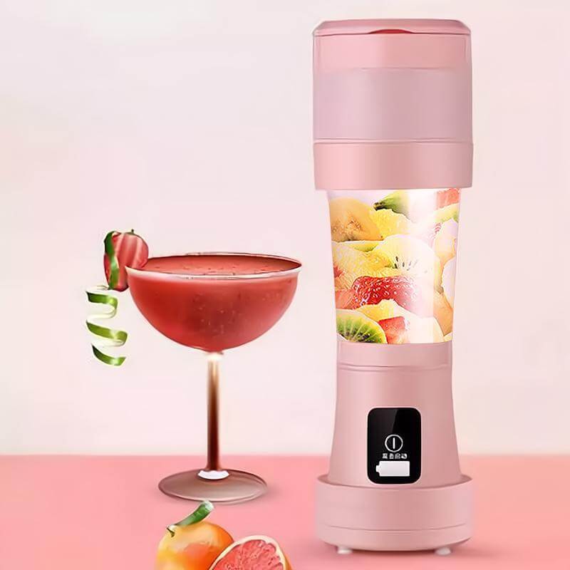 Pink portable blender with sliced fruit inside, next to a fresh smoothie and assorted fruit on a pink surface.