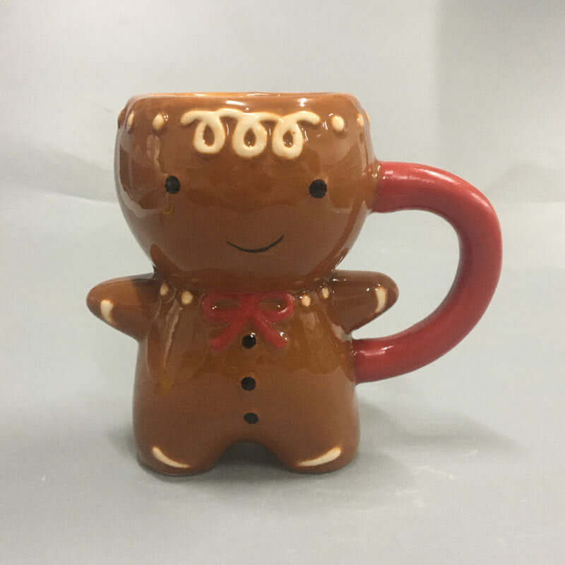 Ceramic gingerbread man mug with red handle, holiday kitchen accessory on grey background.