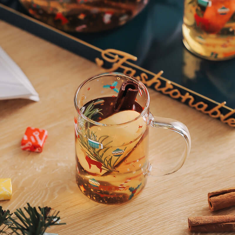 Glass mug with cinnamon stick, apple slice, and herbal tea on wooden table, festive kitchen decor