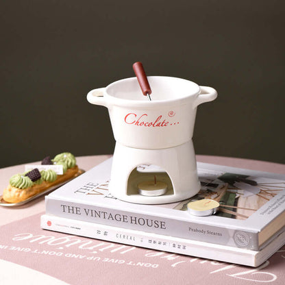 Ceramic chocolate fondue pot with fork and tealight on books, elegant kitchen accessory display