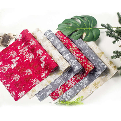 Assorted festive table runners with Christmas tree and snowflake patterns in red, gray, and beige.
